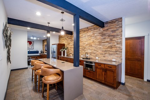 A kitchen with a bar area and a stone wall.