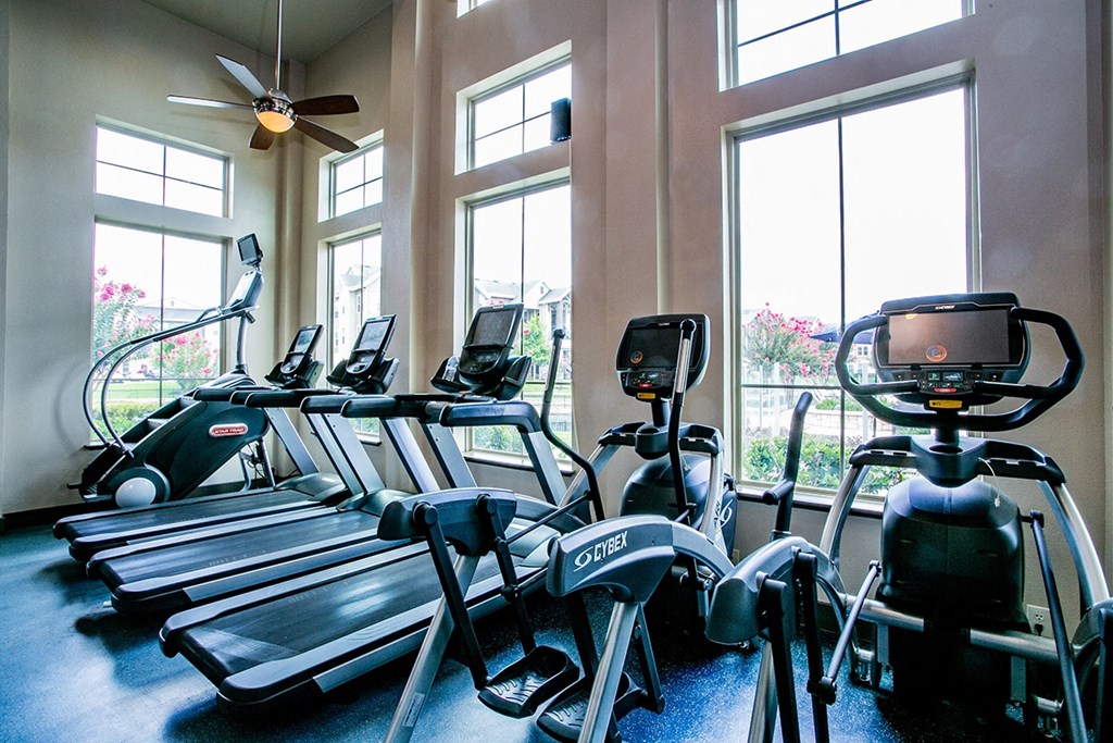 a gym with cardio machines and windows