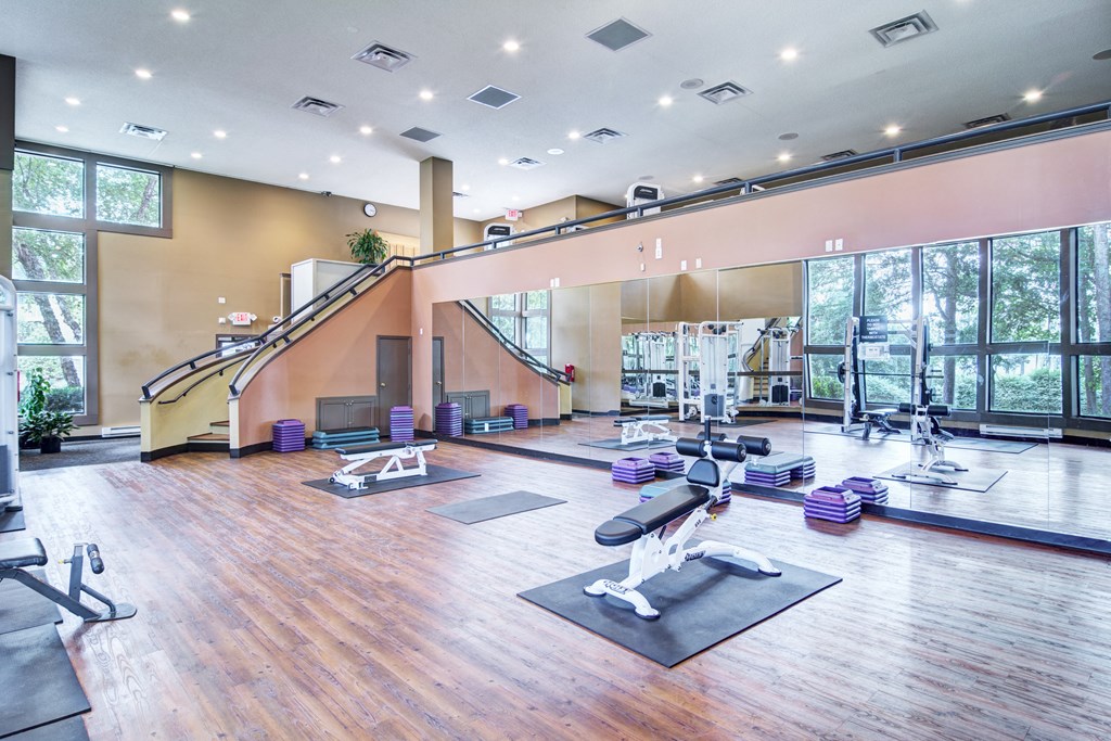 a spacious fitness room with yoga mats and exercise equipment and large windows