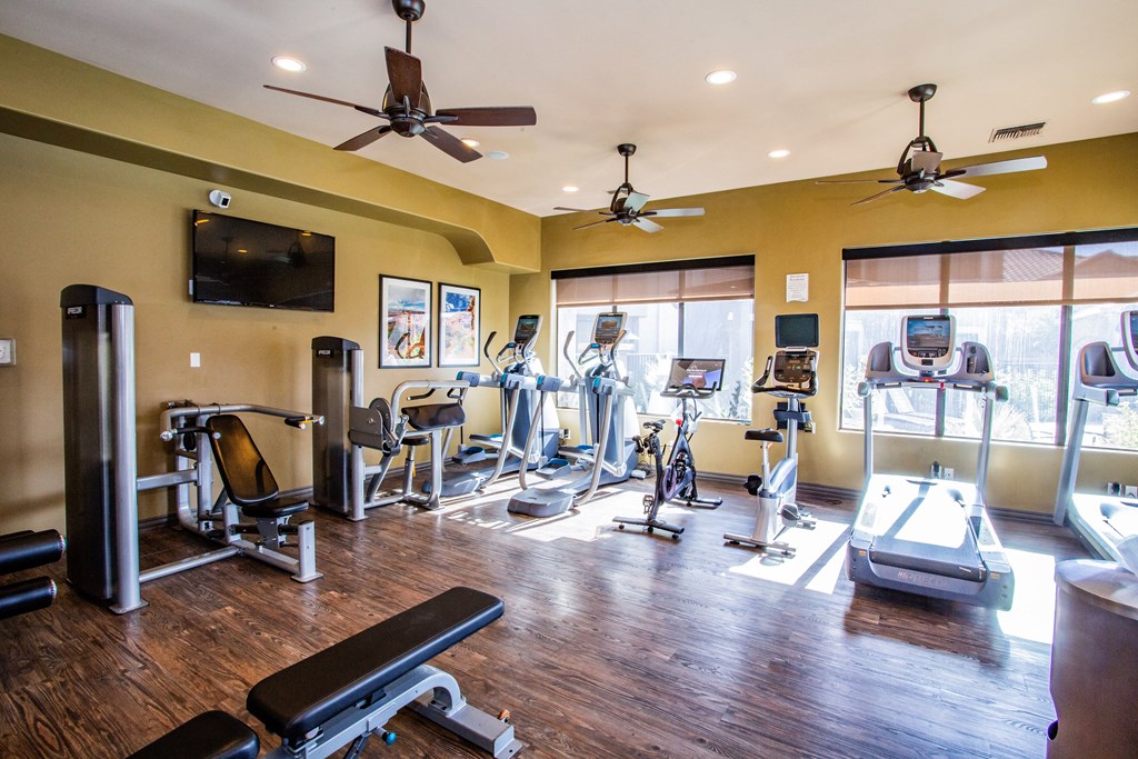 A gym with a variety of equipment including treadmills, weights, and exercise bikes.