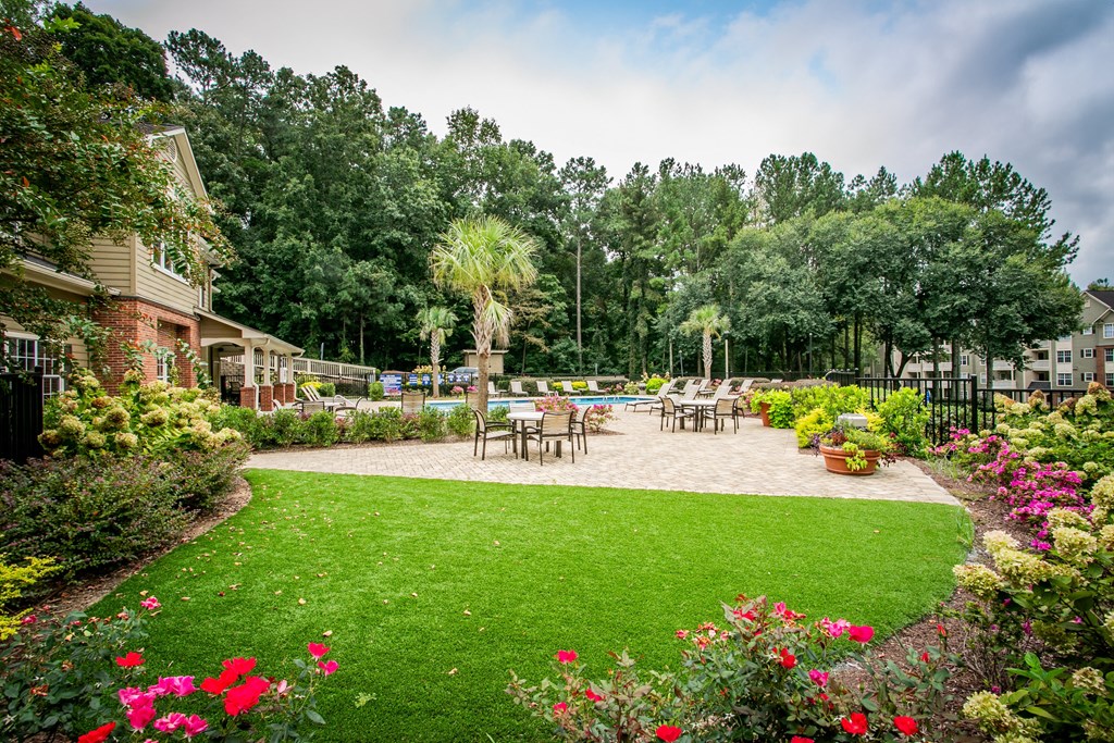 a backyard with a patio and a lawn with tables and chairs