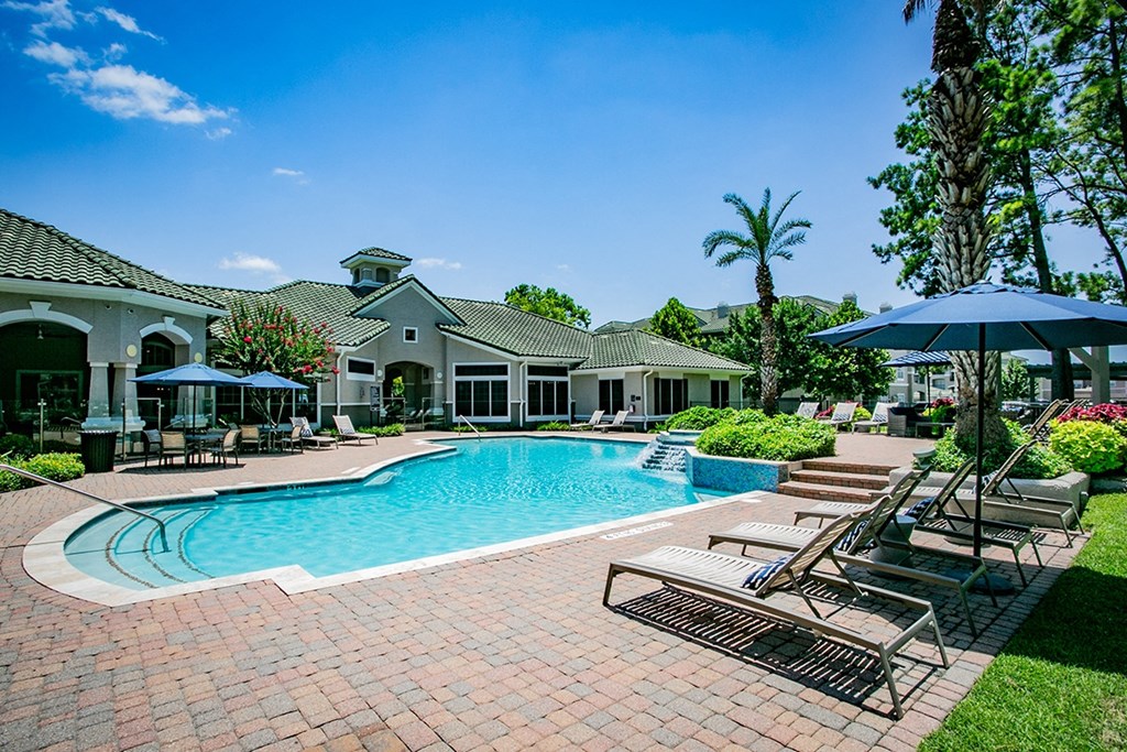 a large swimming pool with lounge chairs and umbrellas