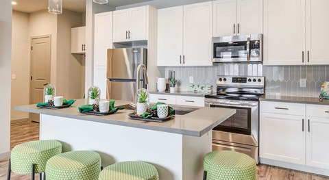 A kitchen with white cabinets and green stools.