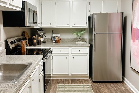 A kitchen with a stainless steel refrigerator and white cabinets.