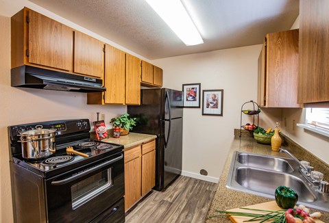 A kitchen with a black stove top oven and black refrigerator.