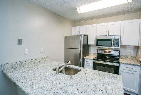 a kitchen with a granite counter top and a stainless steel refrigerator