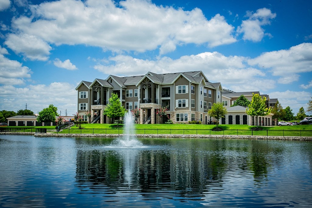 a fountain in the middle of a lake with a large building in the background