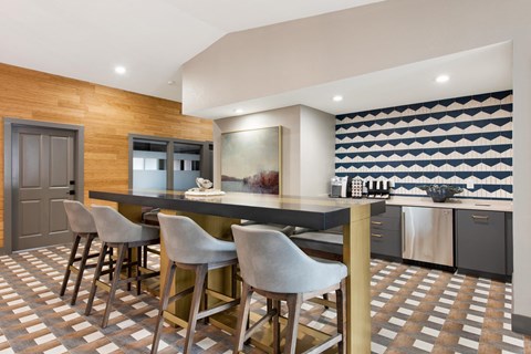 a kitchen with a bar with chairs and a counter