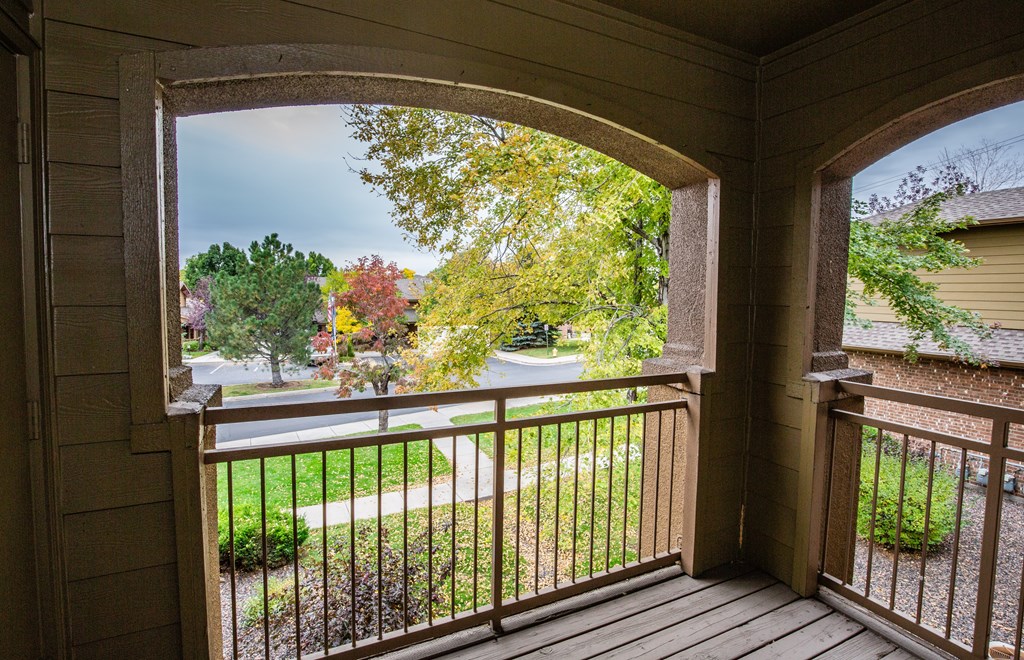 A view from a porch looking out to a street lined with trees.