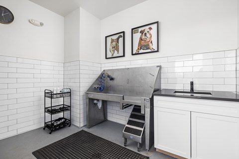 A kitchen with white cabinets and a black and white tiled wall.