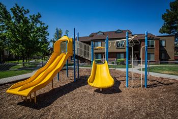 A playground with a yellow slide and a blue handrail.