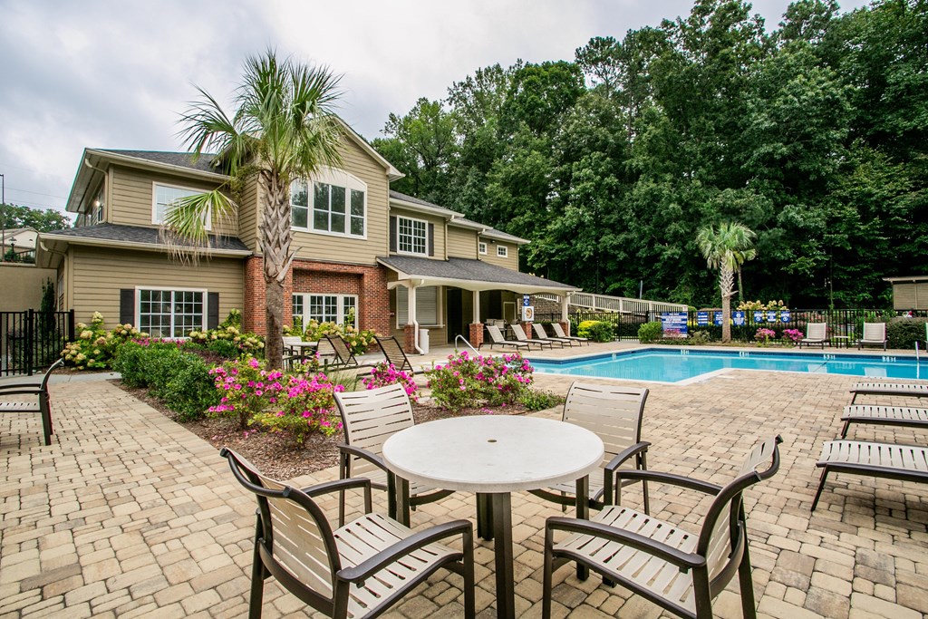 a patio with chairs and a pool in front of a house