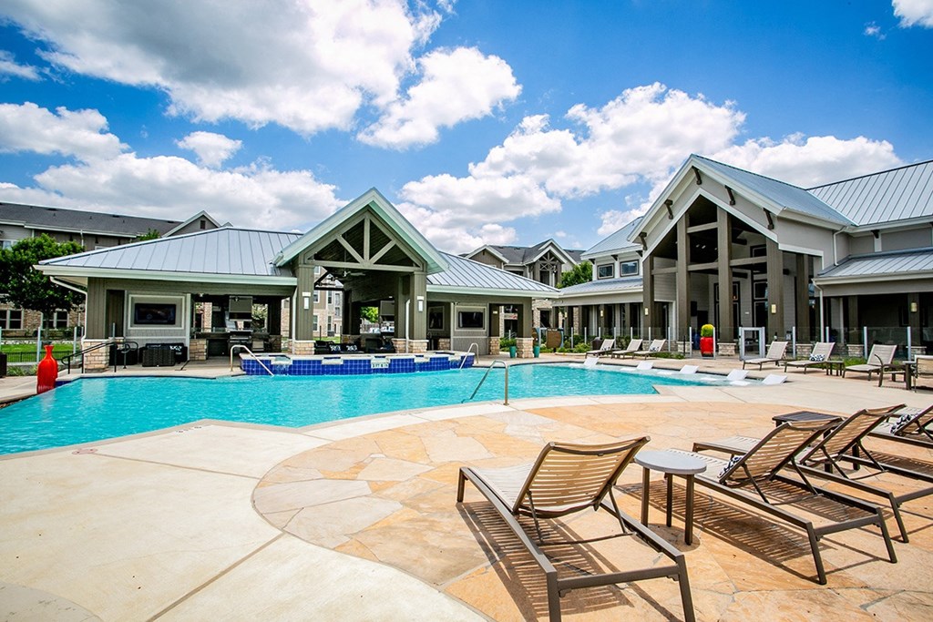 a resort style swimming pool with lounge chairs and a hot tub