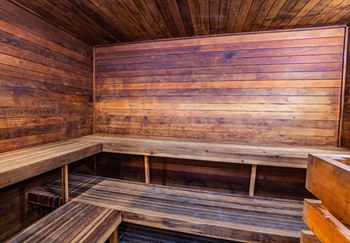 A wooden sauna with benches and a darker wood floor.