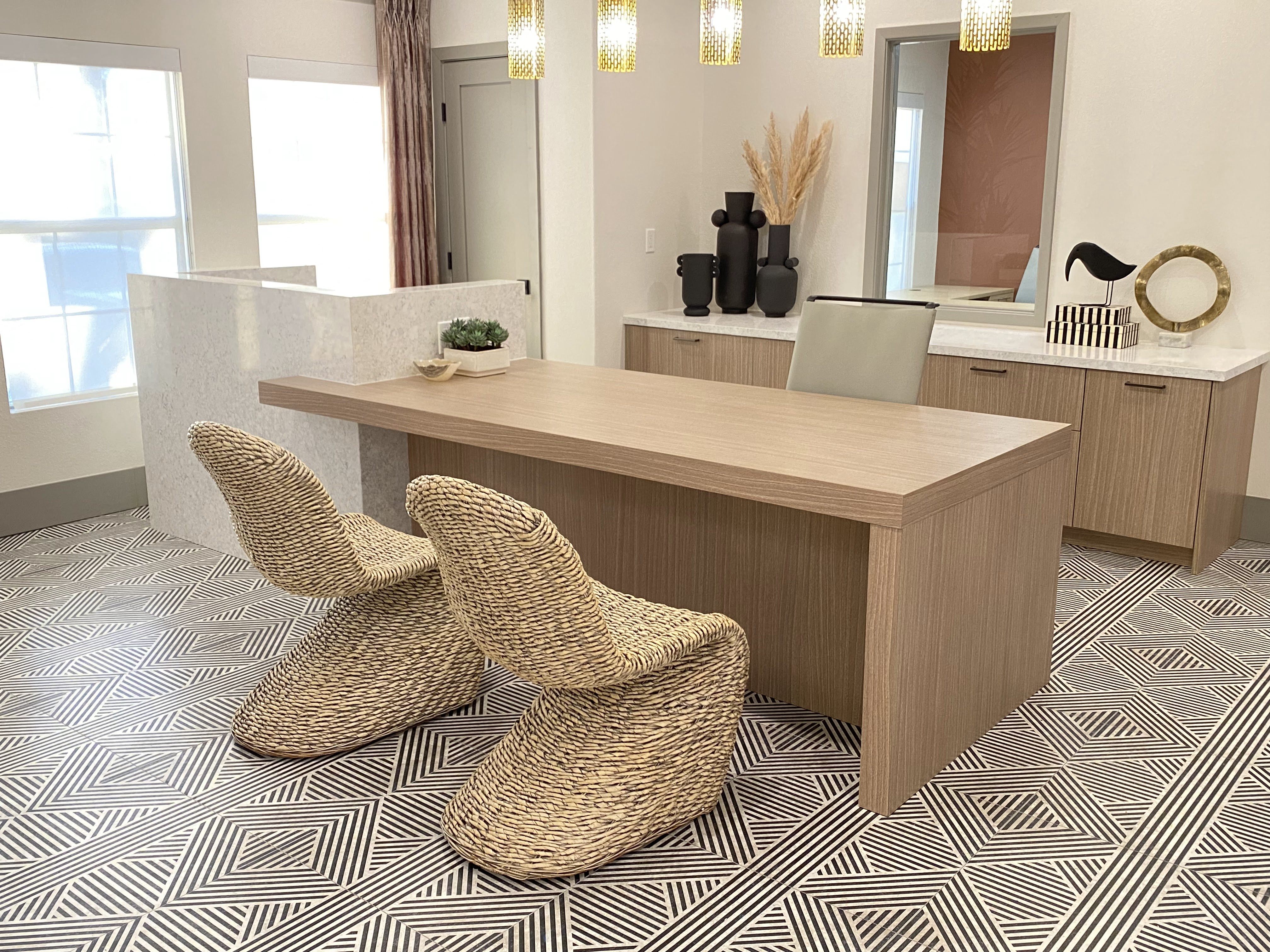 a living room with a wooden desk and two wicker chairs