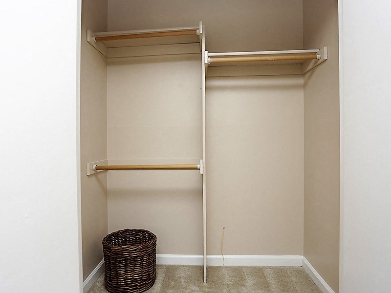 a walk in closet with empty shelves and a basket