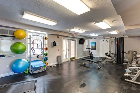 A gym with a variety of equipment including a treadmill, weights, and exercise balls.