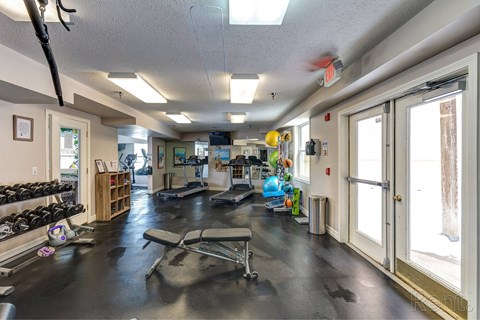 A gym with a variety of equipment including weights, a bench, and a treadmill.