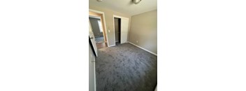 A room with a carpeted floor and two doors.