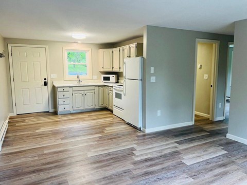 A kitchen with a white refrigerator and wooden floors.