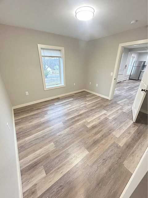 A room with a window and a wooden floor.