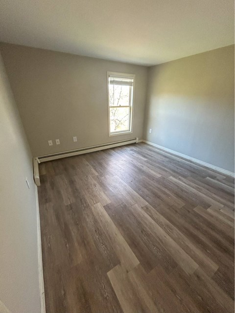 A room with wooden flooring and a window.