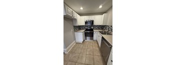 A kitchen with white cabinets and a black stove top oven.