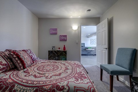 A bedroom with a bed, chair, and a sign on the wall.