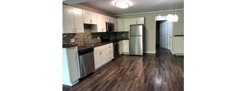 A kitchen with white cabinets and a wooden floor.