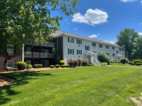 A white two-story apartment building with a green lawn in front.