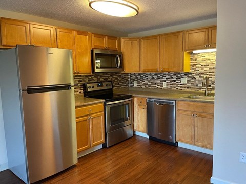 A kitchen with wooden cabinets and a stainless steel refrigerator.