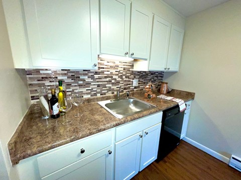A kitchen with a granite countertop and a wine bottle on it.