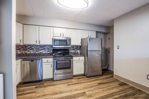 A kitchen with stainless steel appliances and wooden floors.