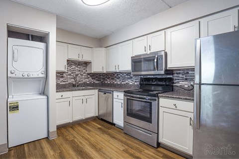 A kitchen with white appliances and wooden floors.