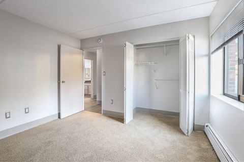 A room with a carpeted floor and a closet with a sliding door.