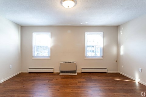 A room with two windows and a wooden floor.
