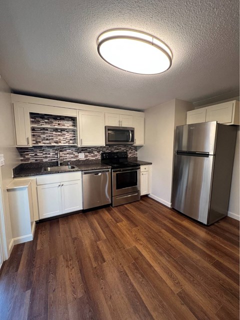 A kitchen with wooden floors and stainless steel appliances.