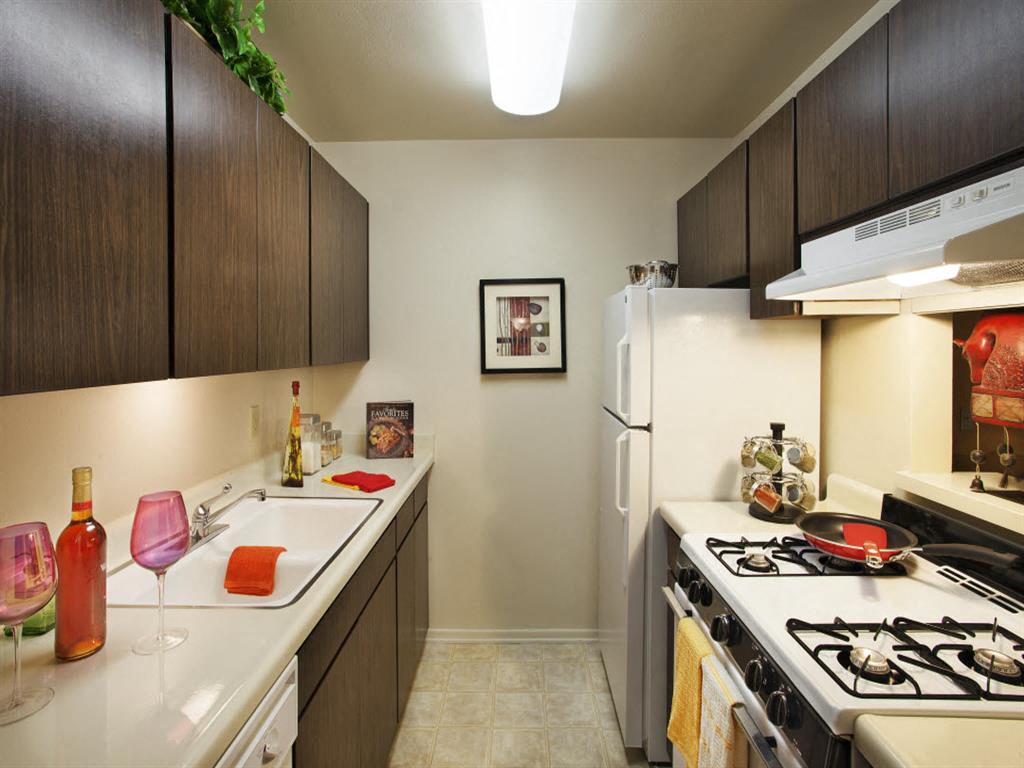 Apartments for Rent in Goleta, CA- Patterson Place- White Granite Countertops With Dark Wood Cabinets And White Stove