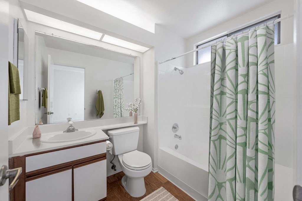 A white bathroom with a green shower curtain.