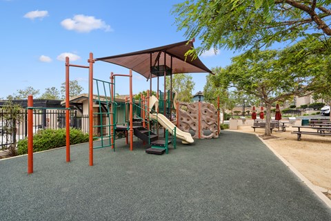 A playground with a green slide and a brown canopy.
