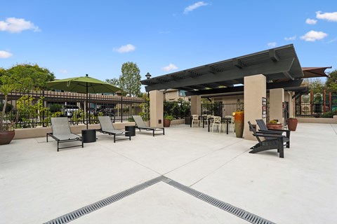 A patio with chairs and a table with a green umbrella.