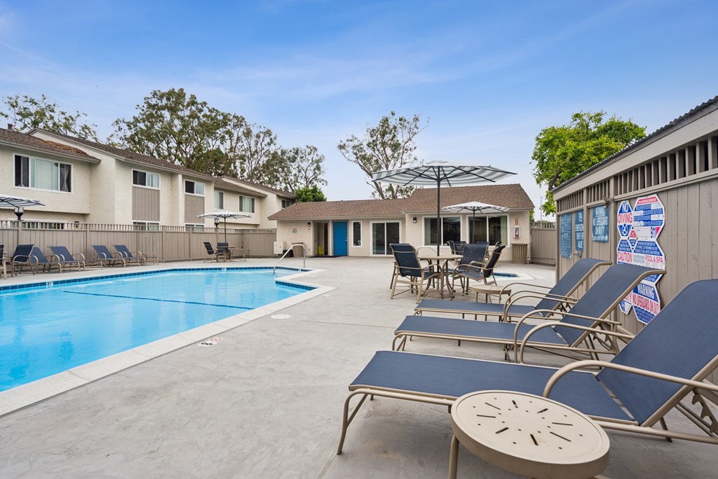 A pool with sun loungers and a building in the background.