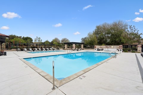 A large outdoor swimming pool with a metal pole in the middle.