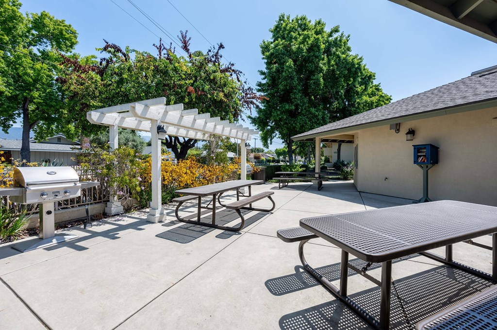 a picnic table with a grill and a pergola at the enclave at woodbridge apartments