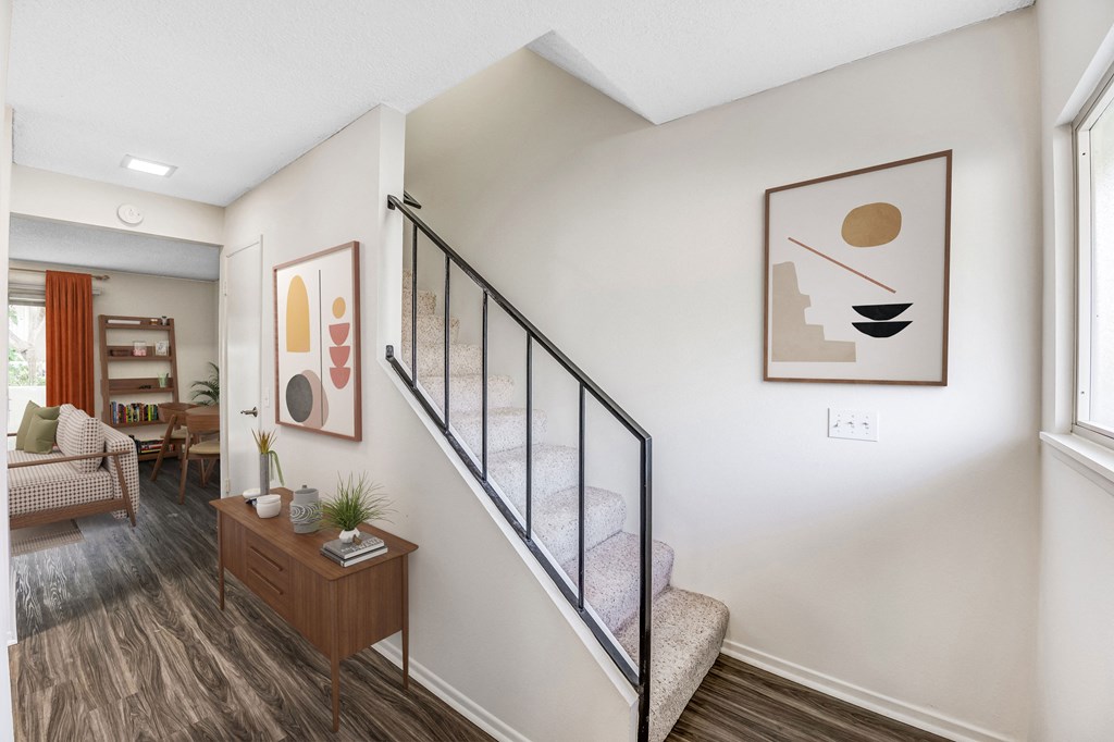 a bedroom with a staircase and a living room in the background