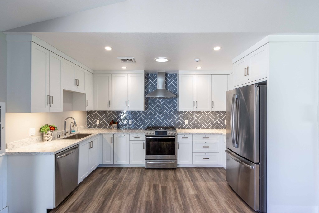 a kitchen with white cabinets and stainless steel appliances