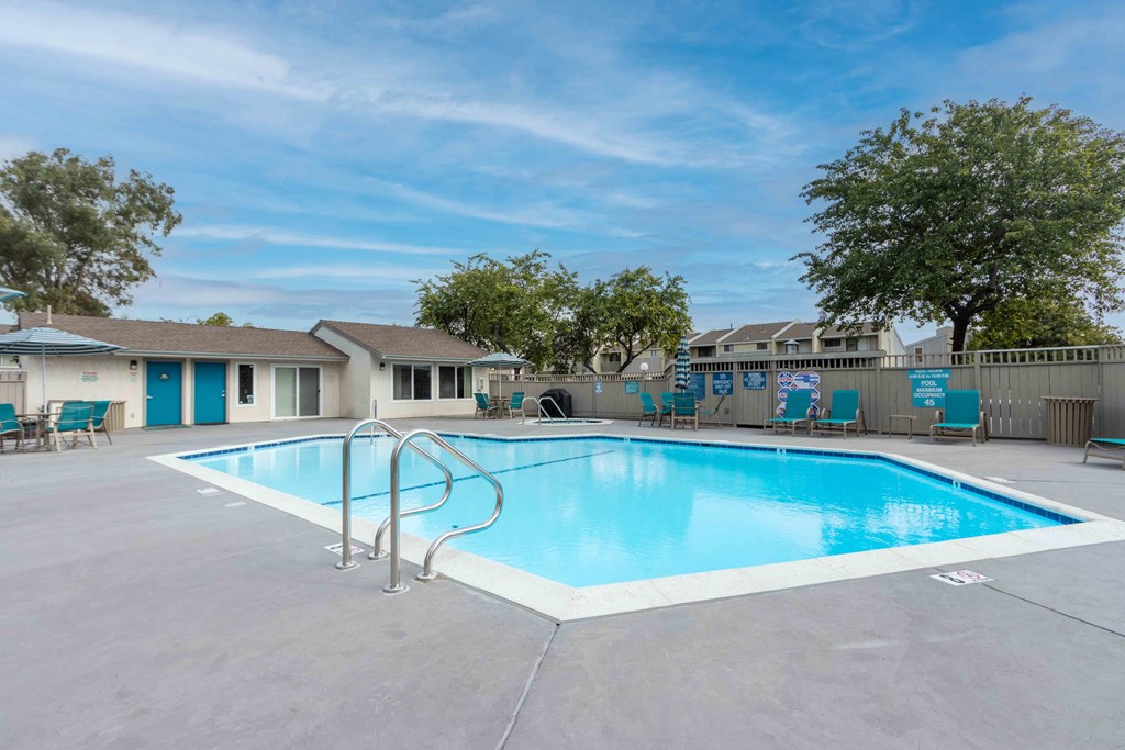 our resort style swimming pool is next to our apartments with a fence and trees