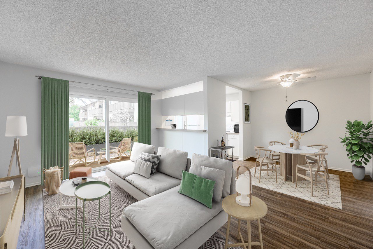 A modern living room with a grey sofa and a round mirror on the wall.