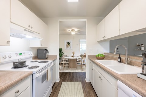 A kitchen with white cabinets and a wooden floor.