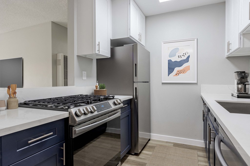 an open kitchen with stainless steel appliances and white counters and a refrigerator